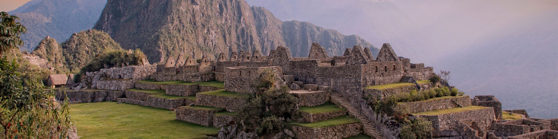 Ruinas de Machu Picchu con campos en terrazas y una montaña al fondo.