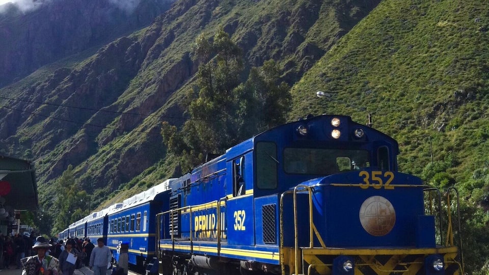 A blue train numbered 352 at a station with people waiting.