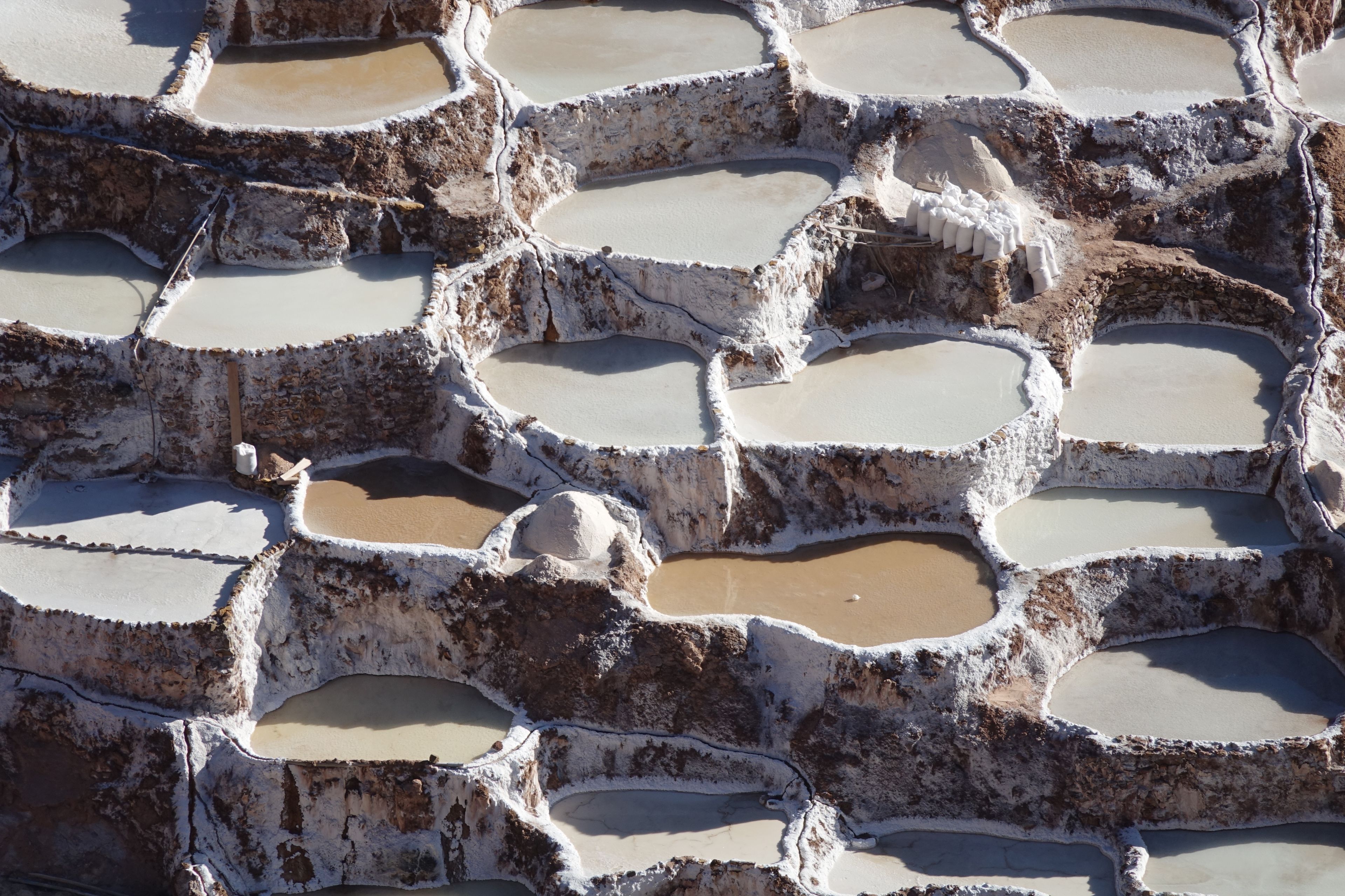 Piscinas escalonadas con depósitos minerales blancos y agua marrón.