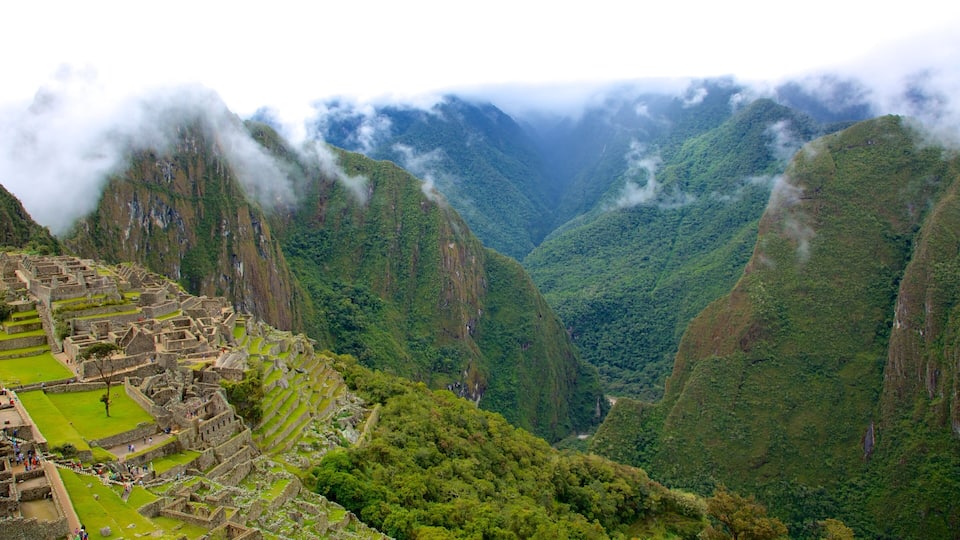 Machu Picchu ruins amidst lush green mountains and misty clouds.