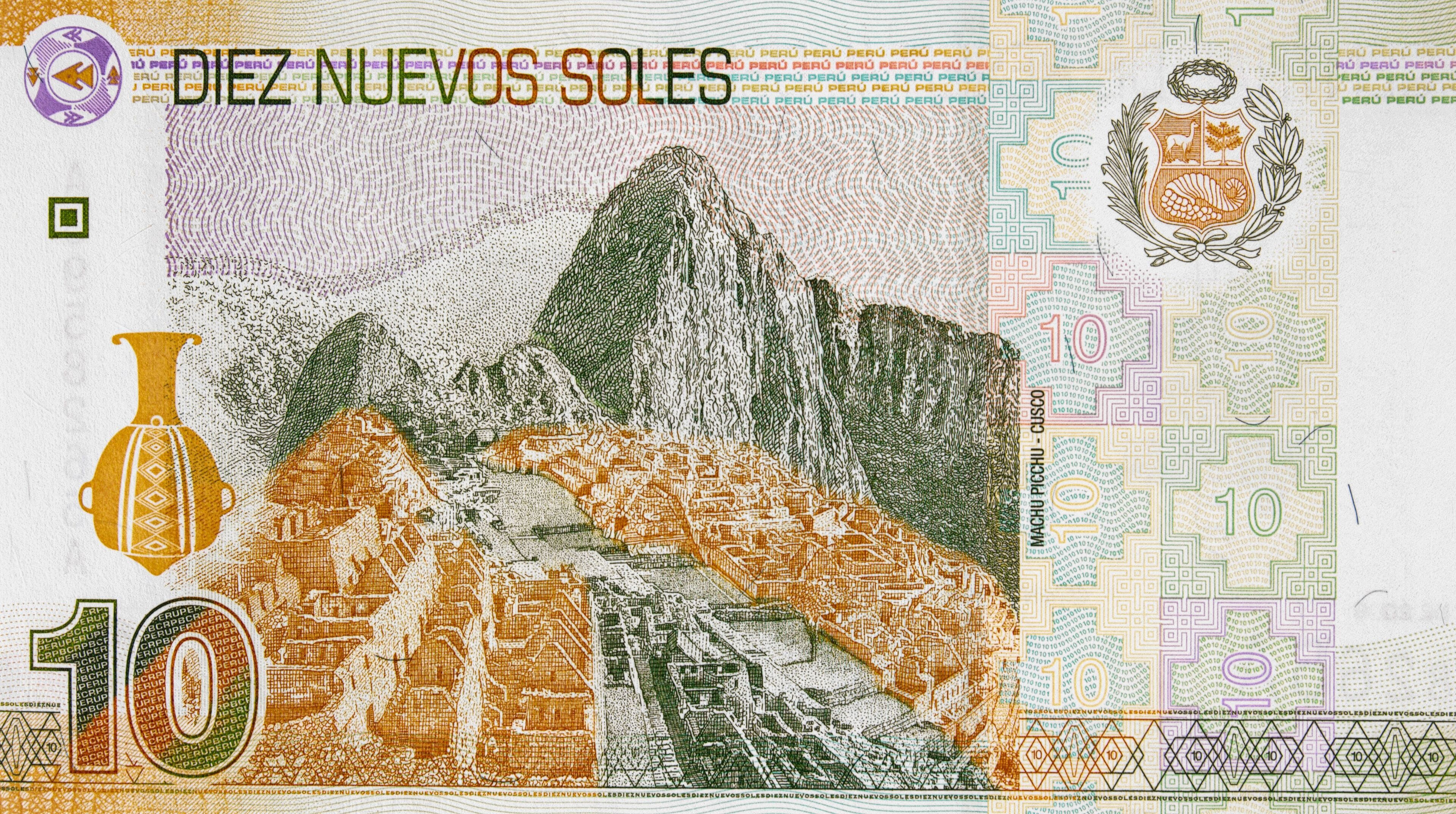 Un billete peruano con un paisaje de montaña, un jarrón y la denominación '10'.