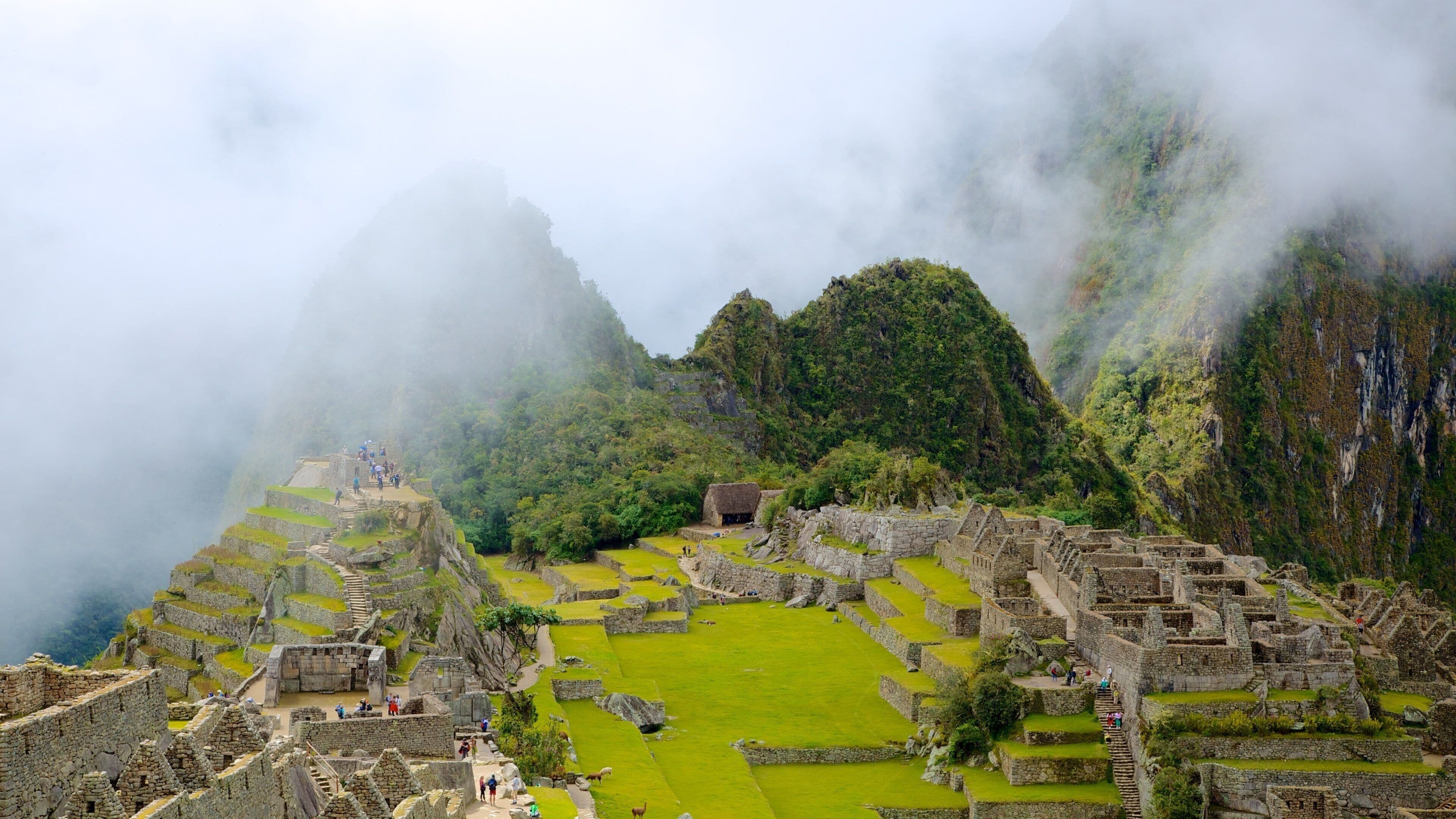 The ruins of Machu Picchu with steep mountain backdrops and mist.