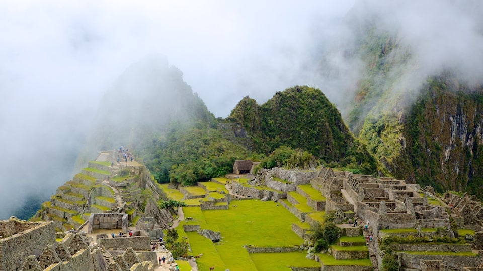 The ruins of Machu Picchu with steep mountain backdrops and mist.