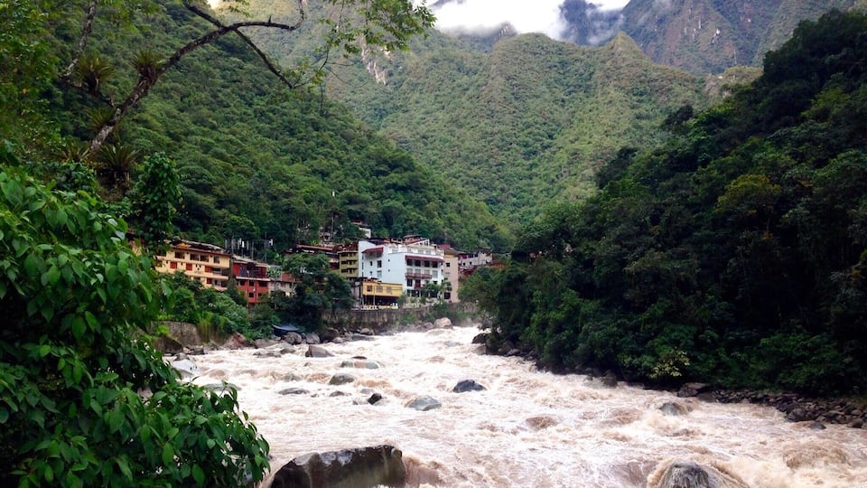 A river with a bridge, surrounded by lush greenery and mountains.