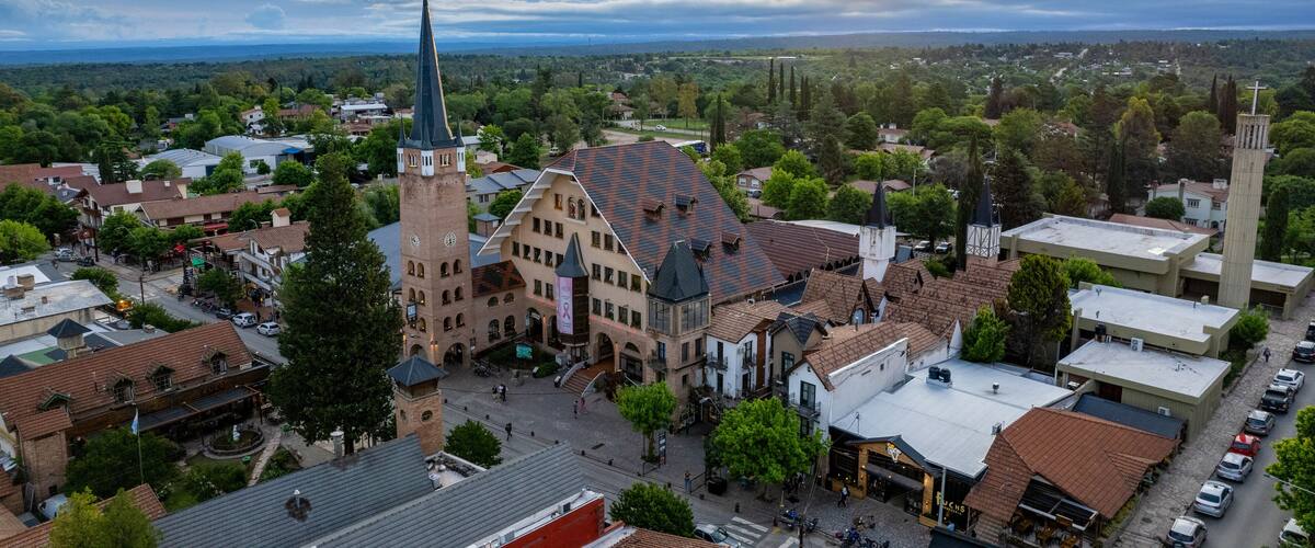A town with a prominent church featuring a tall spire and a clock tower, surrounded by historic buildings and a cobblestone street.