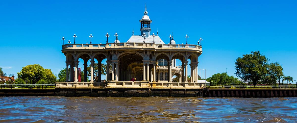 A gazebo with a dome and columns by a river.