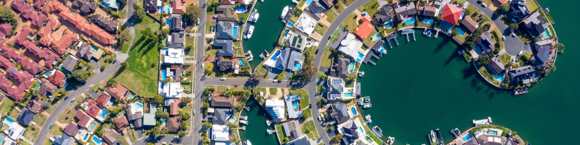 Uma área residencial costeira com um calhavete circular rodeado por casas e barcos.