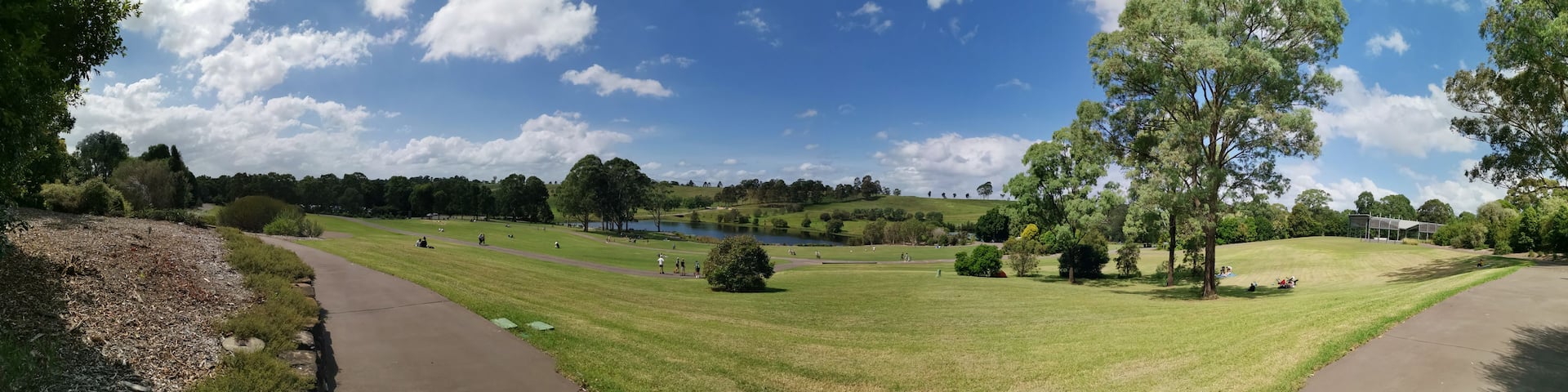 A park with a lake, walking paths, and grassy areas.