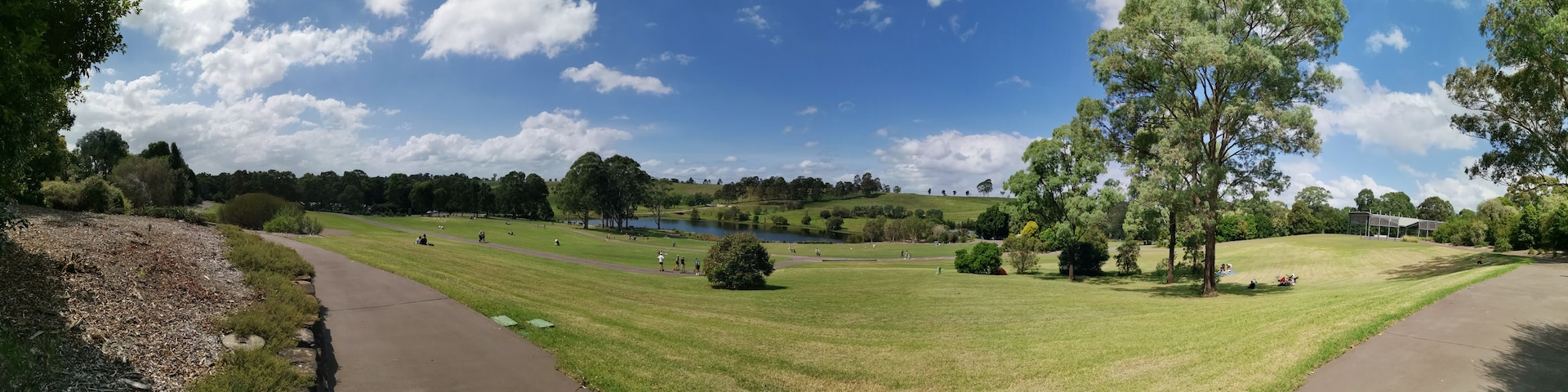 Un parque con un lago, senderos peatonales y zonas verdes.