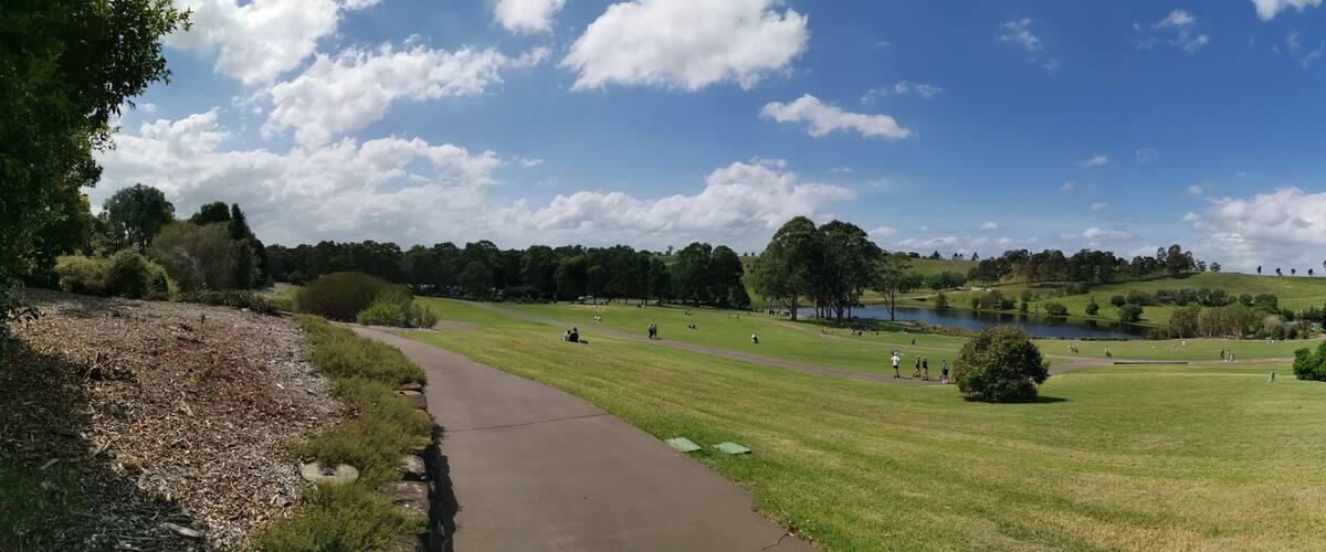 A park with a lake, walking paths, and grassy areas.
