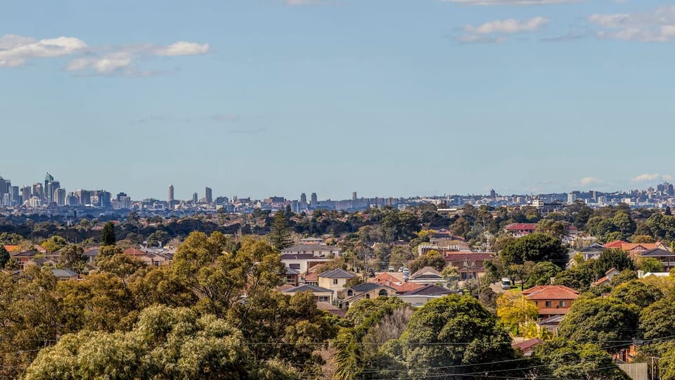 Paisagem urbana com uma área residencial densa em primeiro plano e um horizonte de arranha-céus ao fundo.
