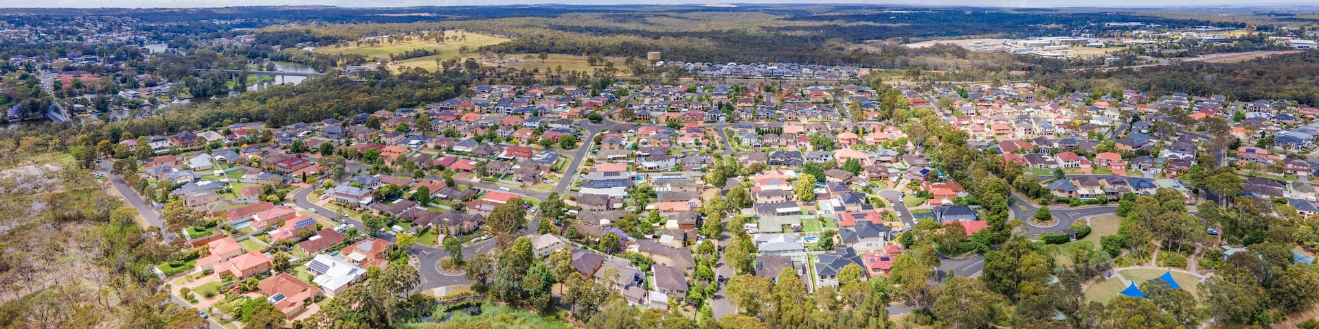 An aerial view of a residential area with houses, roads, and a river.
