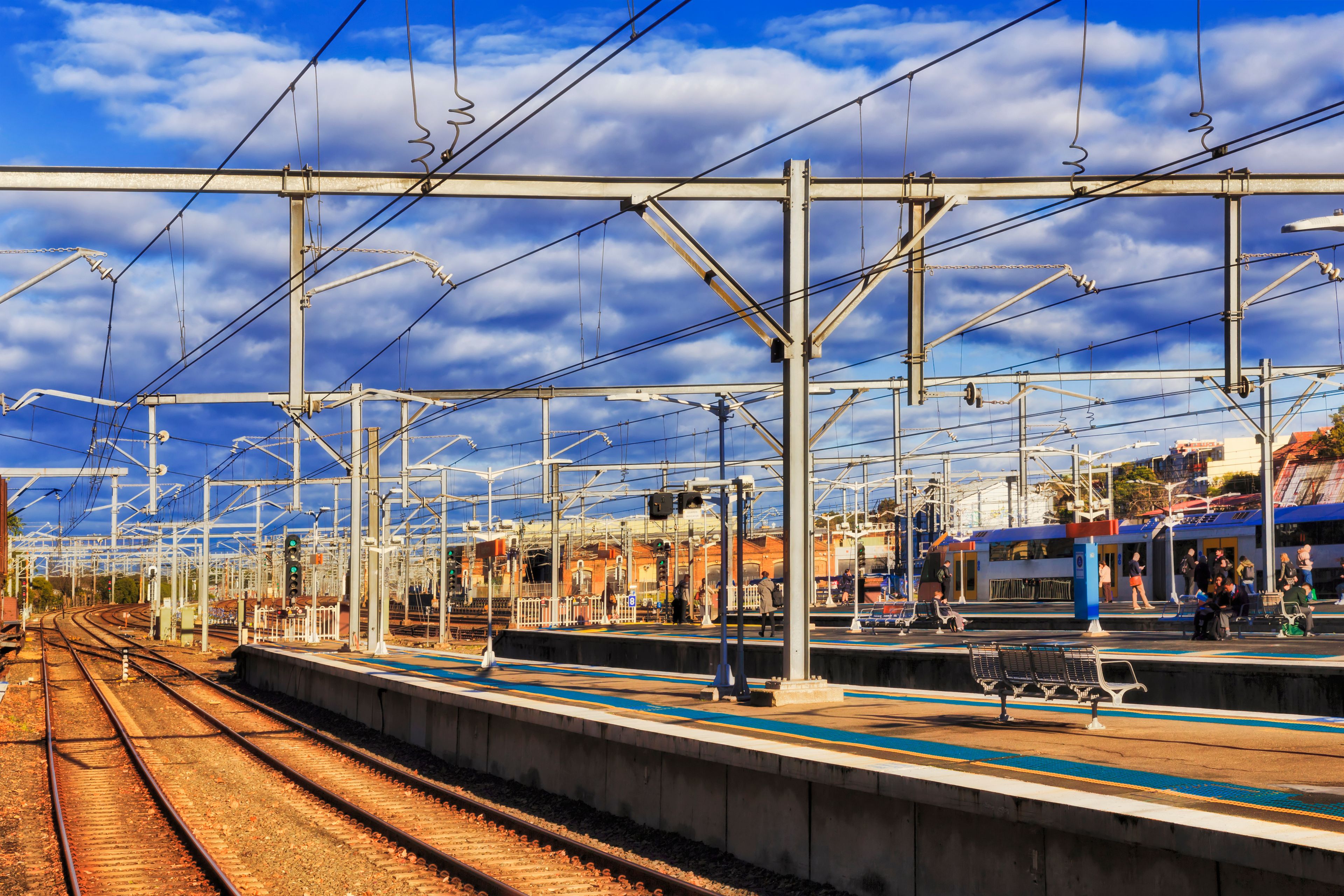 A railway station with multiple tracks and overhead electric lines.