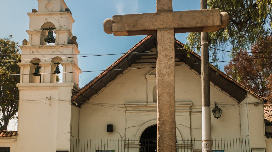 Une église dotée d’un clocher et d’une grande croix en pierre devant l’entrée.