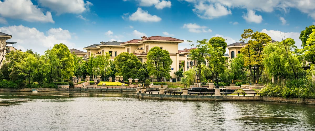 A waterfront residential area with houses, trees, and a calm river.