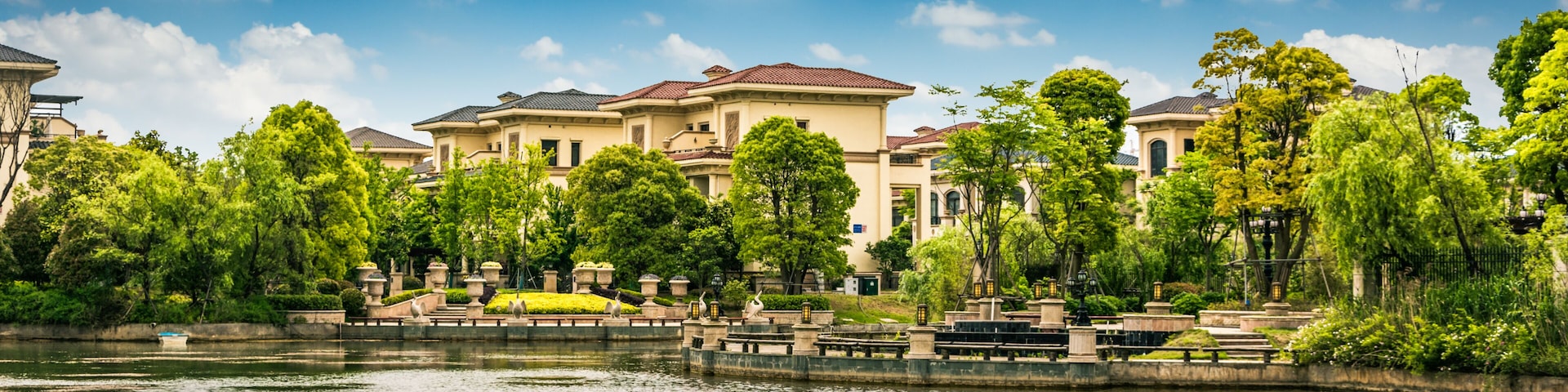 A waterfront residential area with houses, trees, and a calm river.