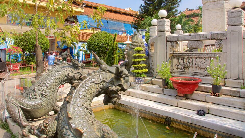 A dragon fountain with water spouting from its mouth, surrounded by stone steps and potted plants.