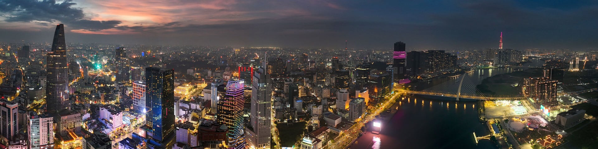 Vast panoramic night view of Ho Chi Minh City skyline at sunset with illuminated skyscrapers and the Saigon River