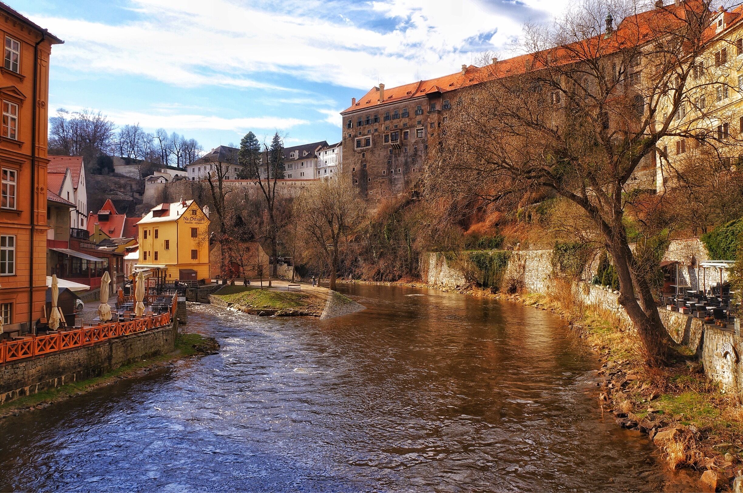 Un río serpentea por un pueblo con edificios históricos y un puente.