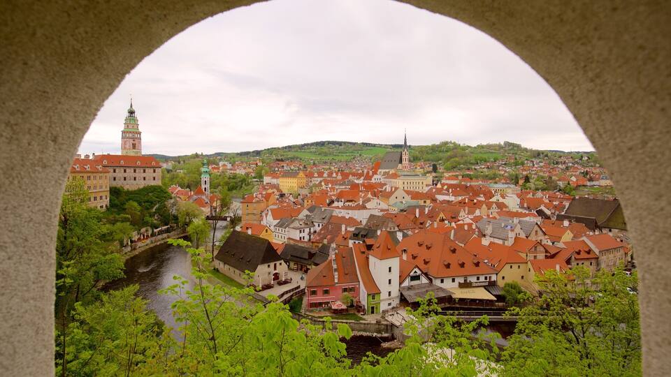 A historic town with red-roofed buildings, a river, and a prominent church tower.