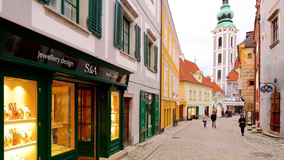 A cobblestone street lined with colorful buildings, including a jewelry store and a cafe.