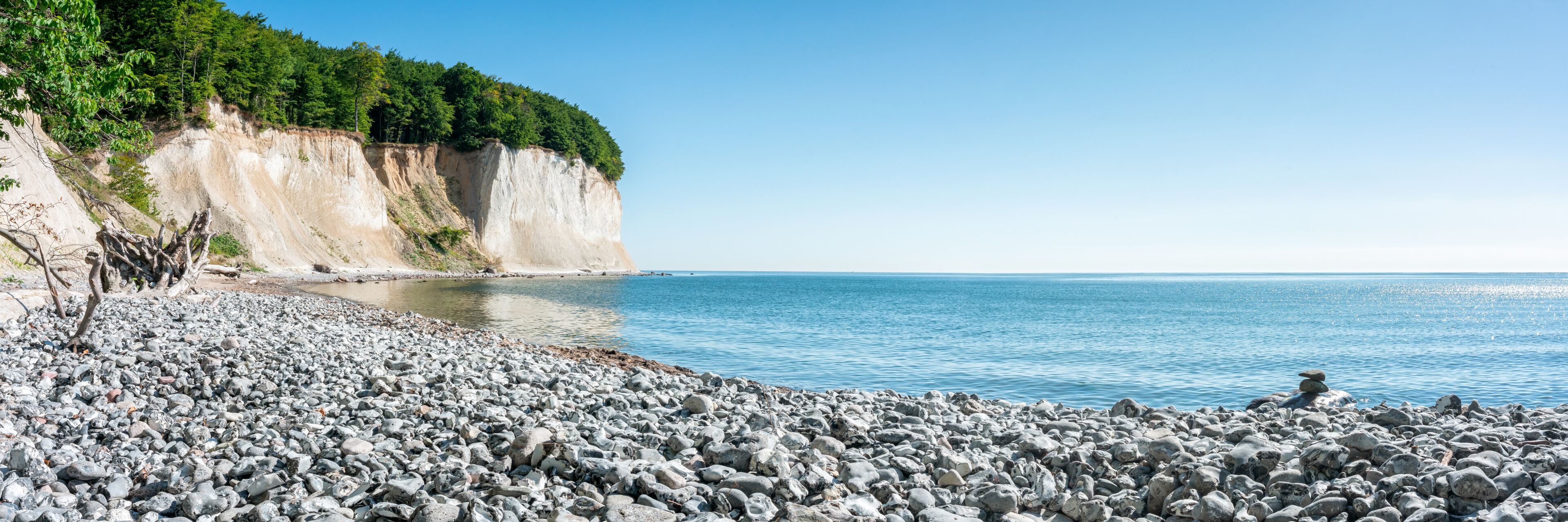 A rocky beach with cliffs and a clear blue sea.