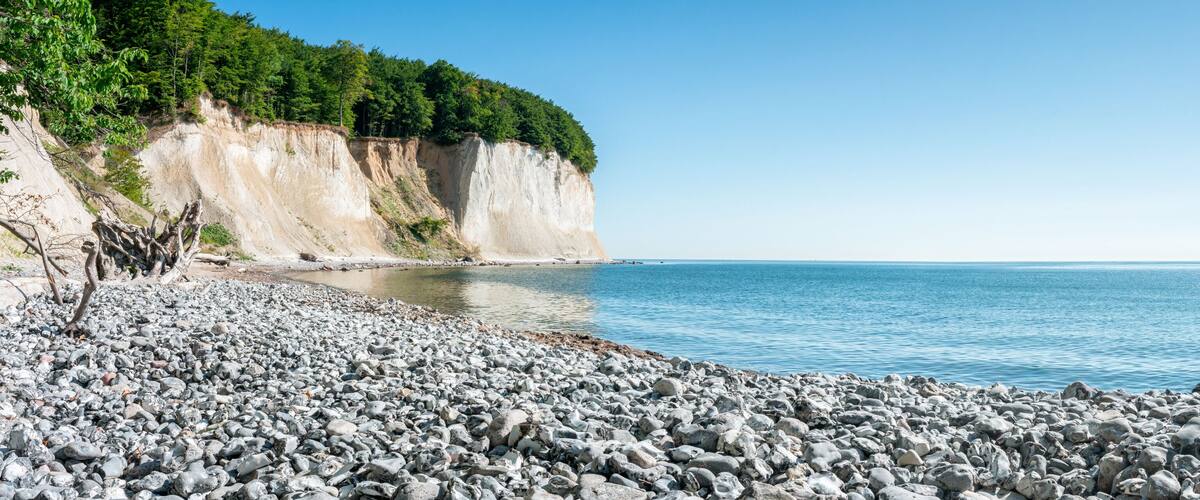 A rocky beach with cliffs and a clear blue sea.