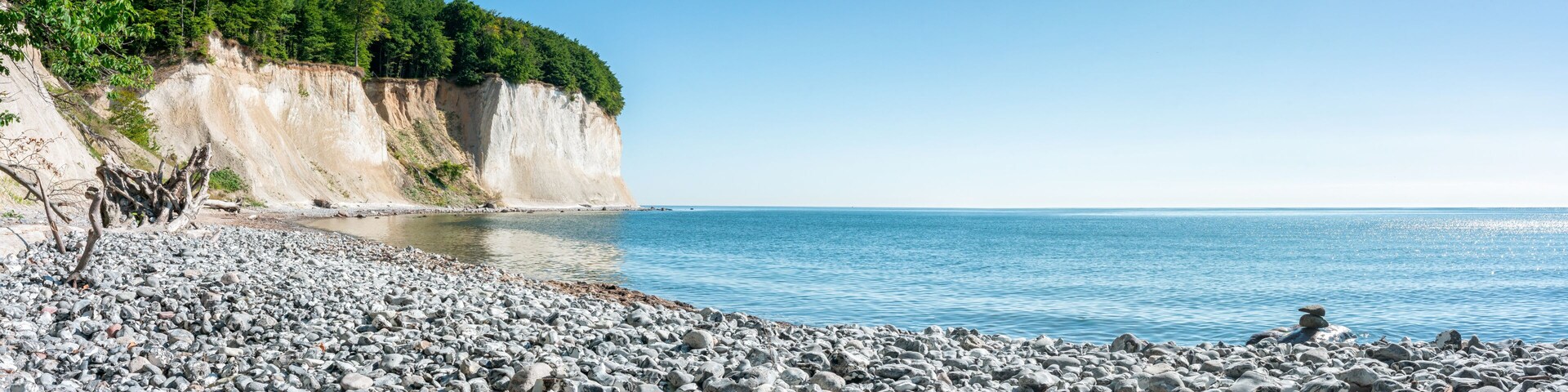 A rocky beach with cliffs and a clear blue sea.