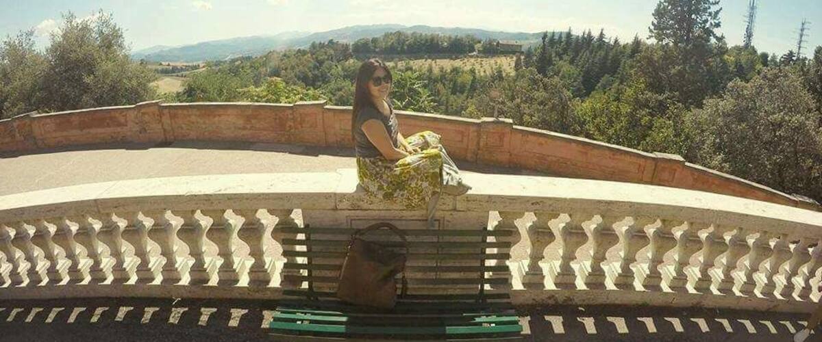A person sitting on a bench in a park with a scenic view of mountains and trees.