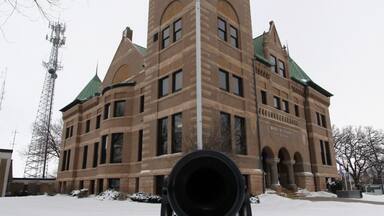 A historic building with a clock tower, an American flag, and a cannon in the foreground.