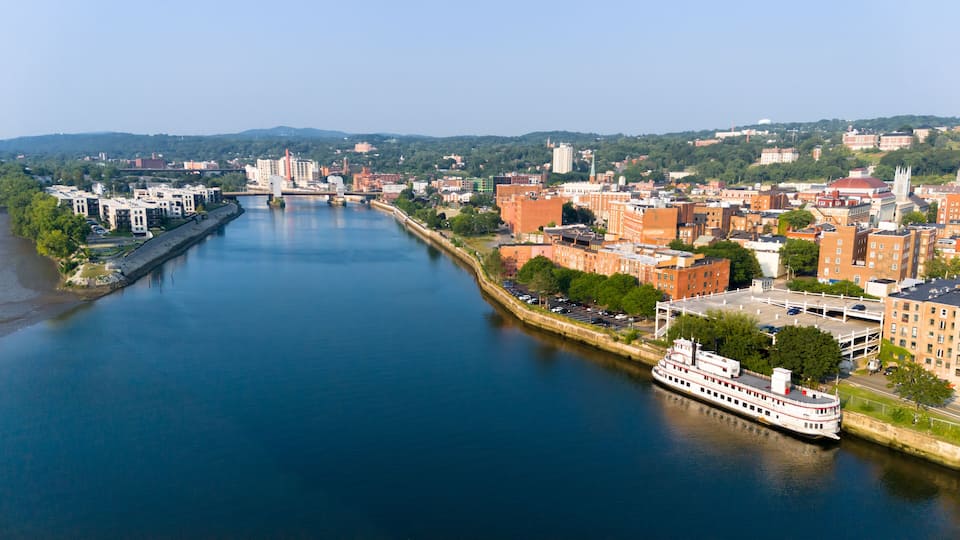 A river with a boat, surrounded by buildings and a bridge.