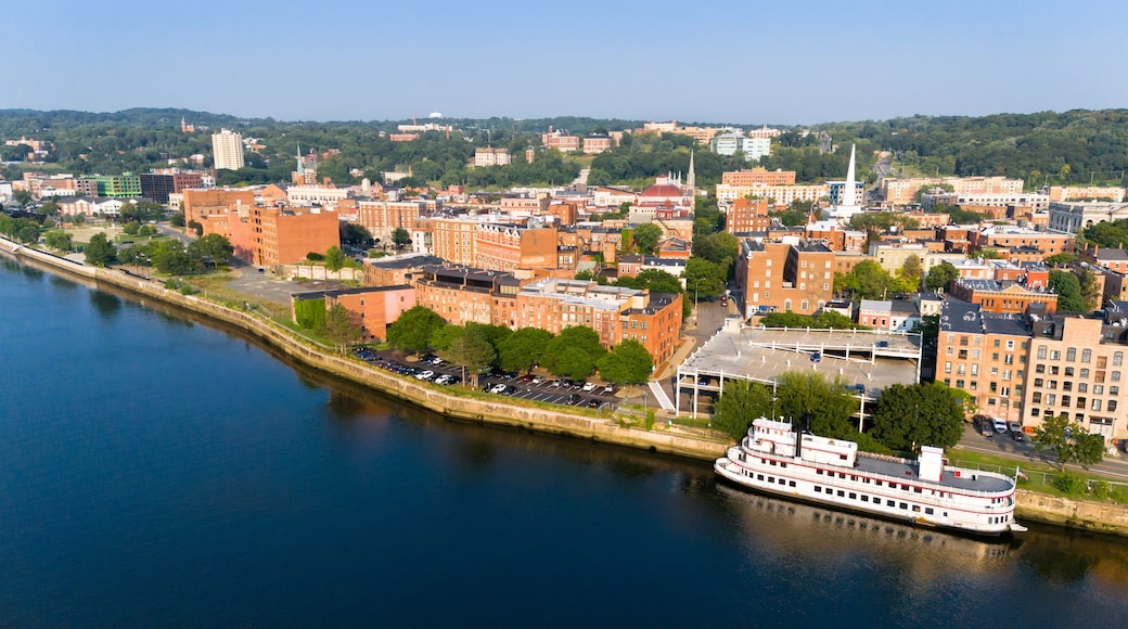 Aerial view of historic downtown Troy, NY, at sunset with docked riverboat and view towards the east along the Hudson River.