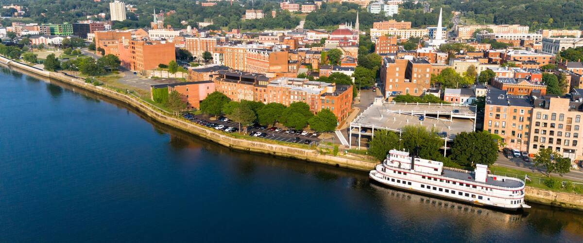 A river with a boat, surrounded by buildings and greenery.