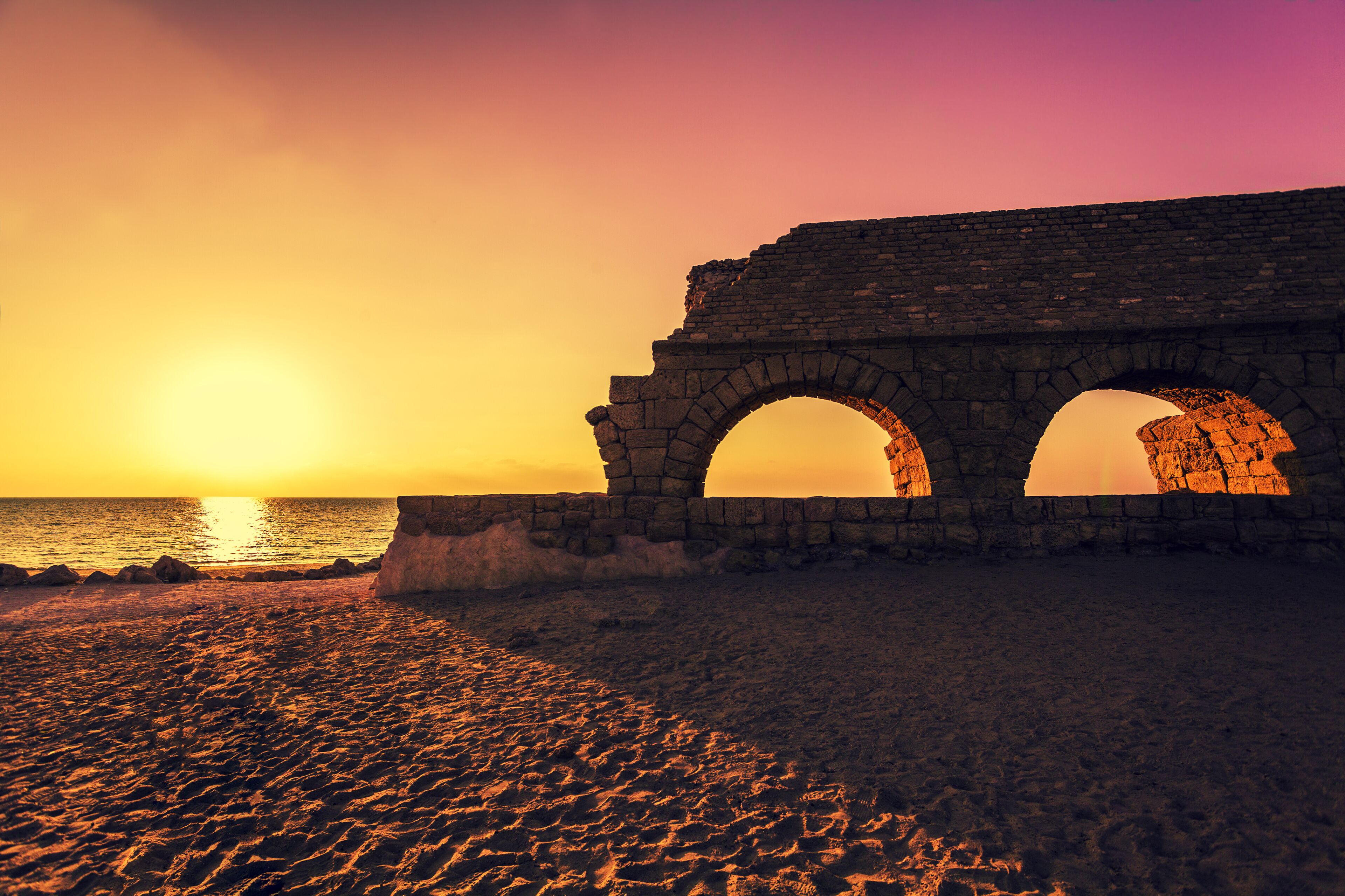 Remains of the ancient Roman aqueduct in ancient city Caesarea at sunset. Israel.