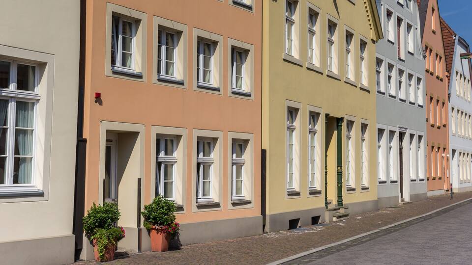 A row of colorful buildings with multiple windows and a cobblestone street.