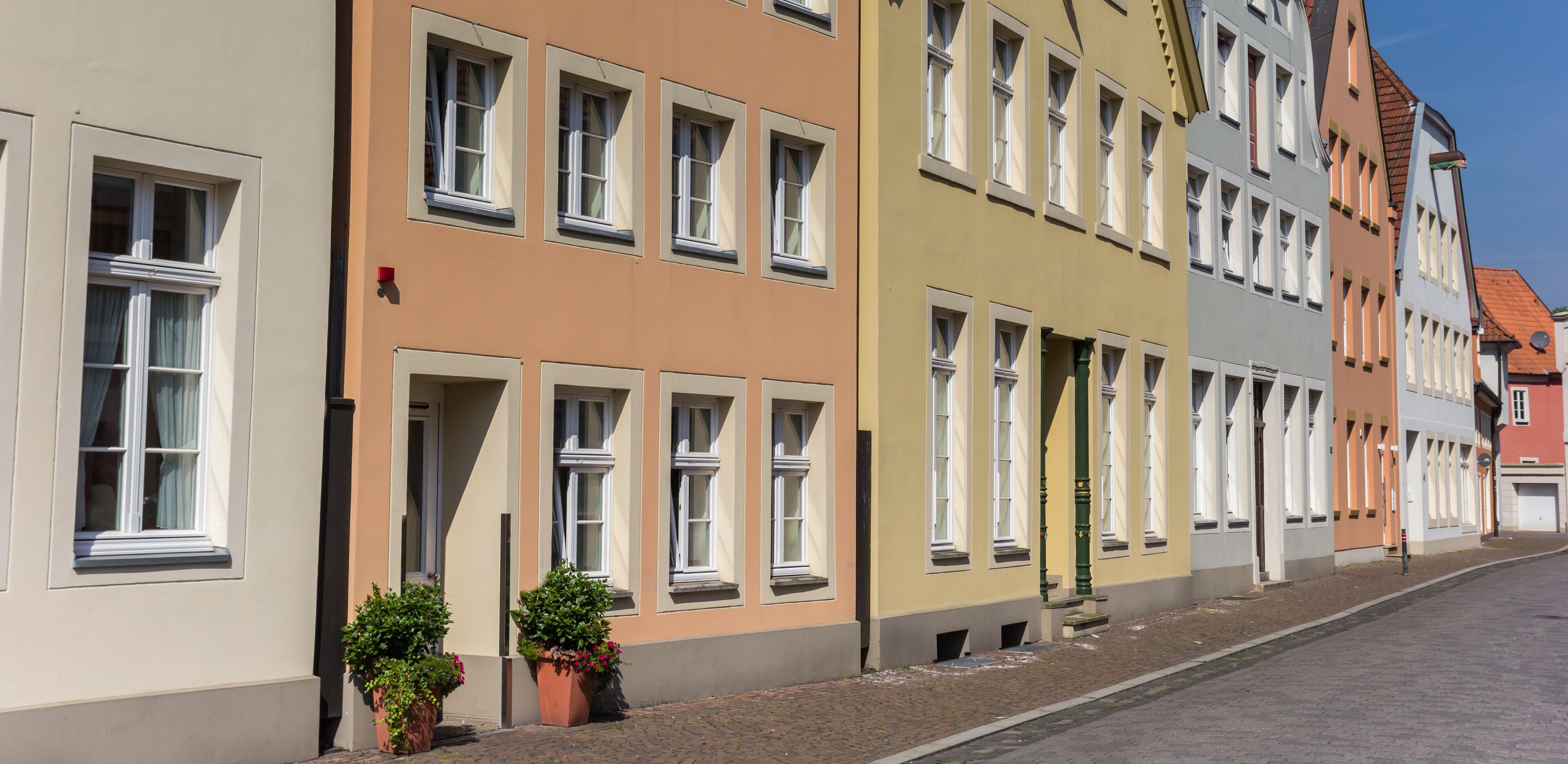 A row of colorful buildings with multiple windows and a cobblestone street.