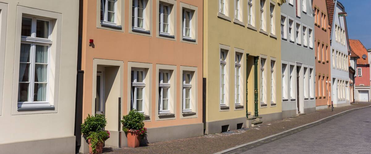 A row of colorful buildings with multiple windows and a cobblestone street.