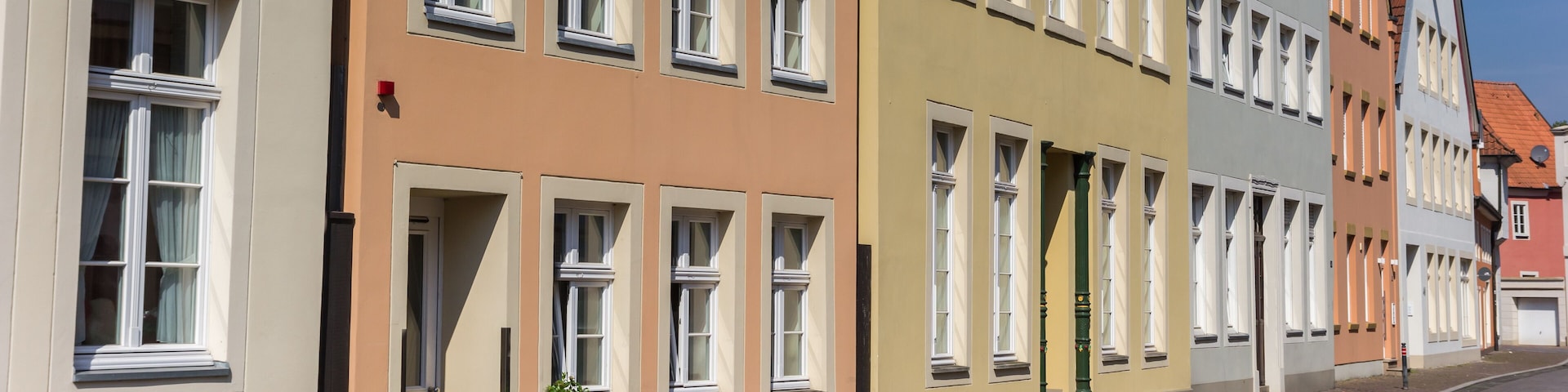A row of colorful buildings with multiple windows and a cobblestone street.