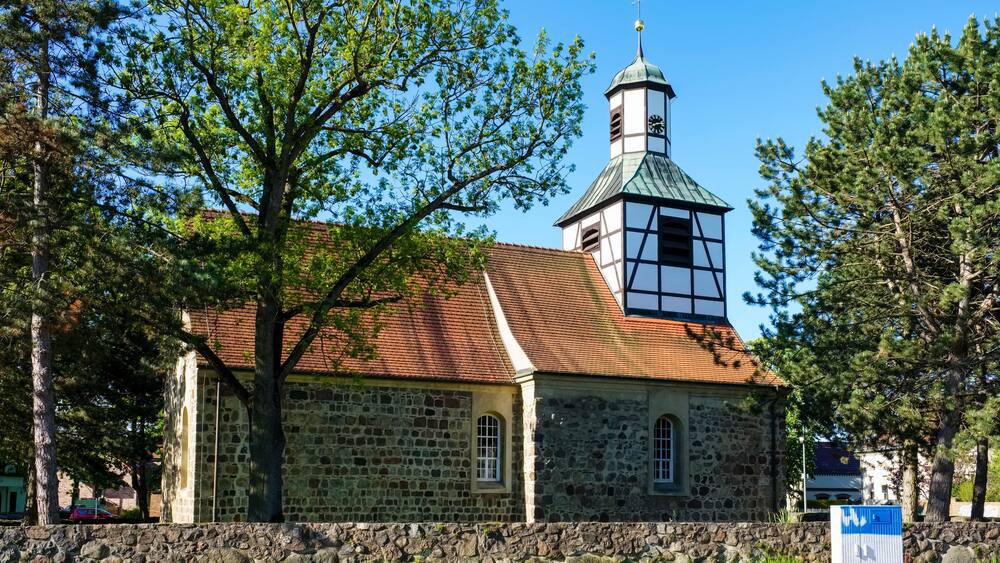 Eine Steinkirche mit einem Glockenturm und einer Mauer im Vordergrund.