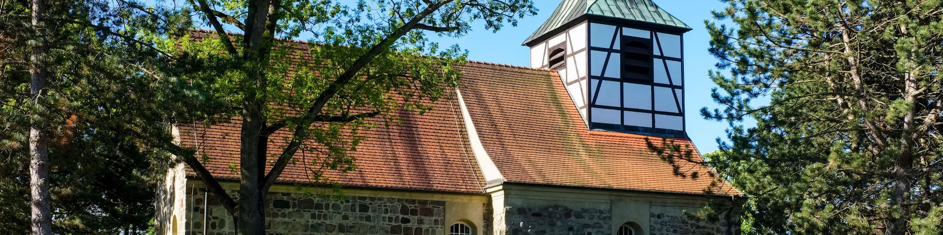 A stone church with a clock tower and a stone wall in front.