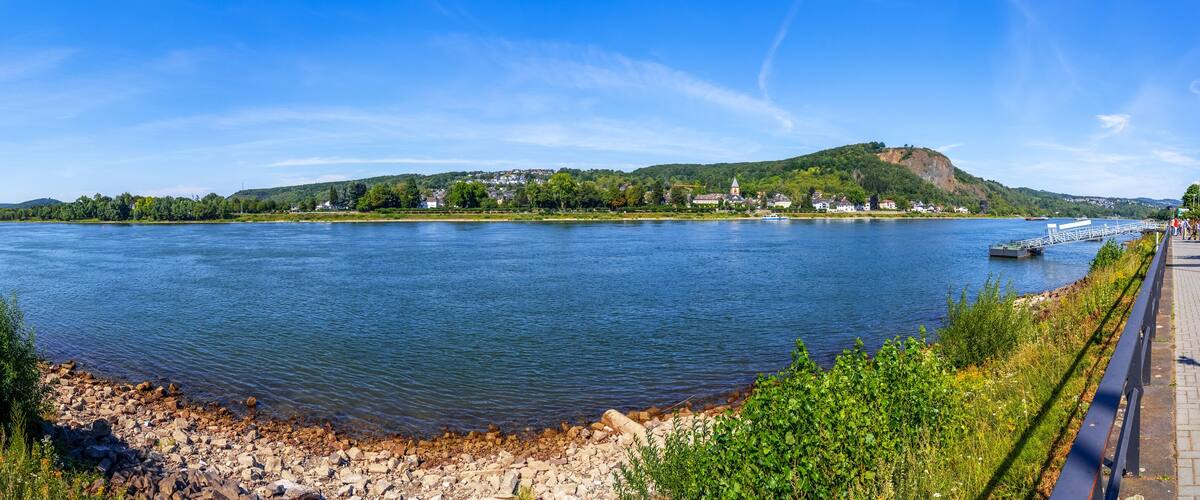 A river with a bridge, a hill with a church, and a row of houses along the riverbank.