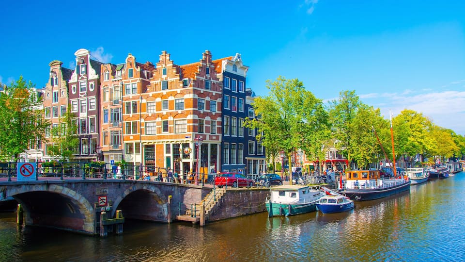 A canal with boats, a bridge, and colorful buildings along the water.