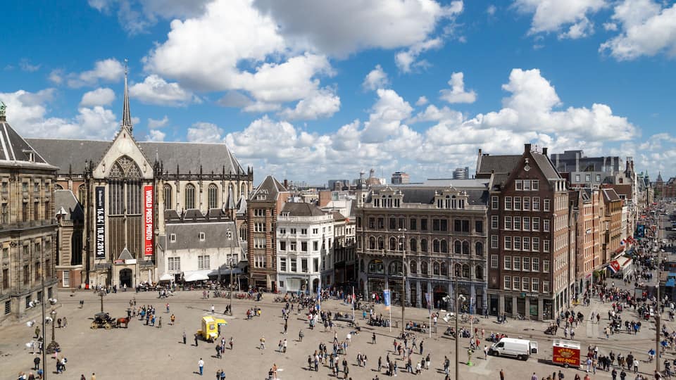 AMSTERDAM, NETHERLANDS - JULY 02, 2016 - Wide view of Dam Square in Amsterdam on cloudy sky background. Dam Square is one of the most popular meeting points in Amsterdam.