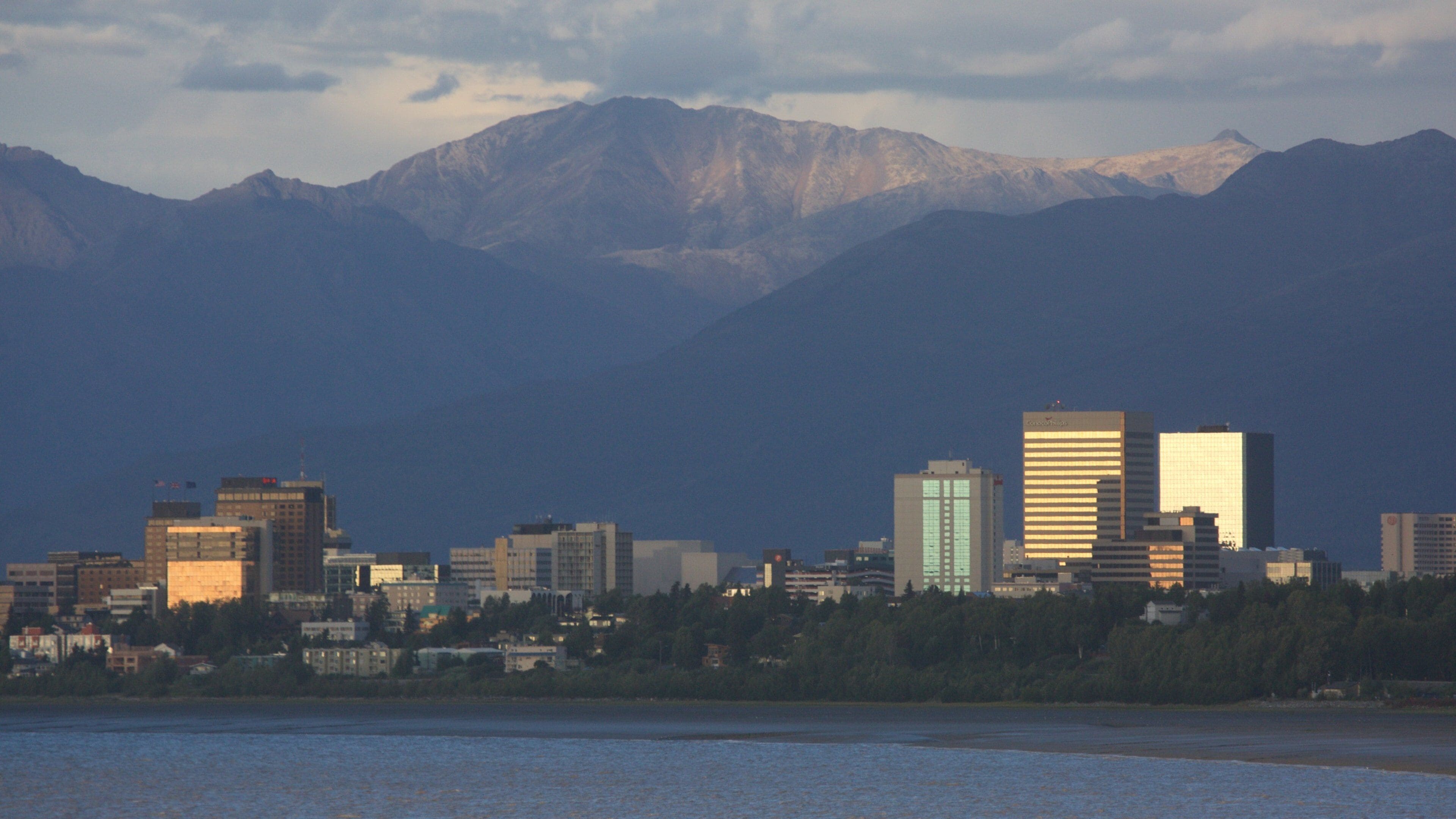 A city skyline with modern buildings and mountains in the background.