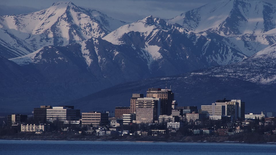 A cityscape with snow-covered mountains in the background.