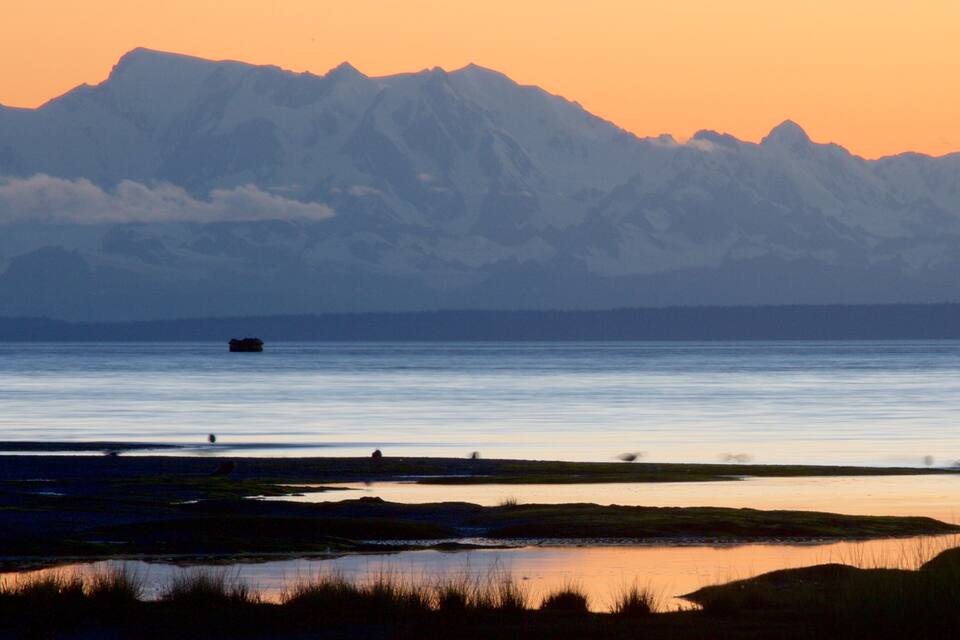 A calm lake with mountains in the background and a small boat in the water.