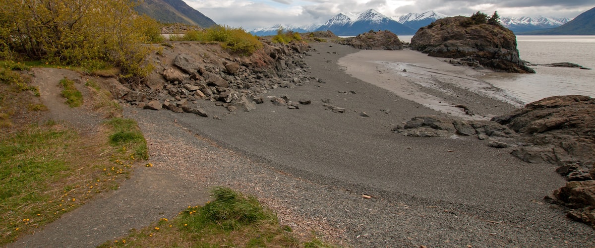 A rocky beach with mountains in the background.