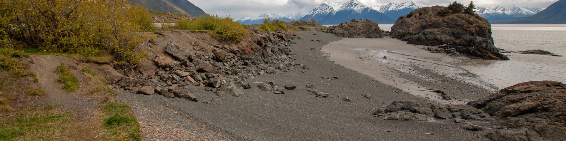 A rocky beach with mountains in the background.