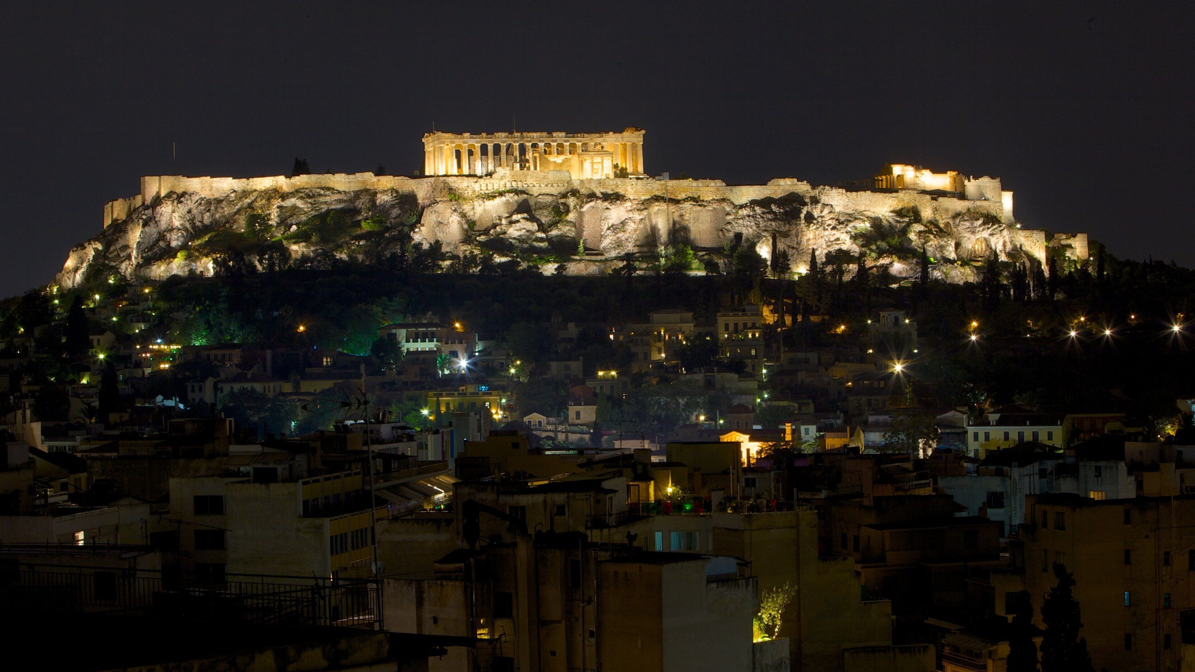 La Acrópolis de Atenas iluminada en la noche, destacándose contra el cielo oscuro.
