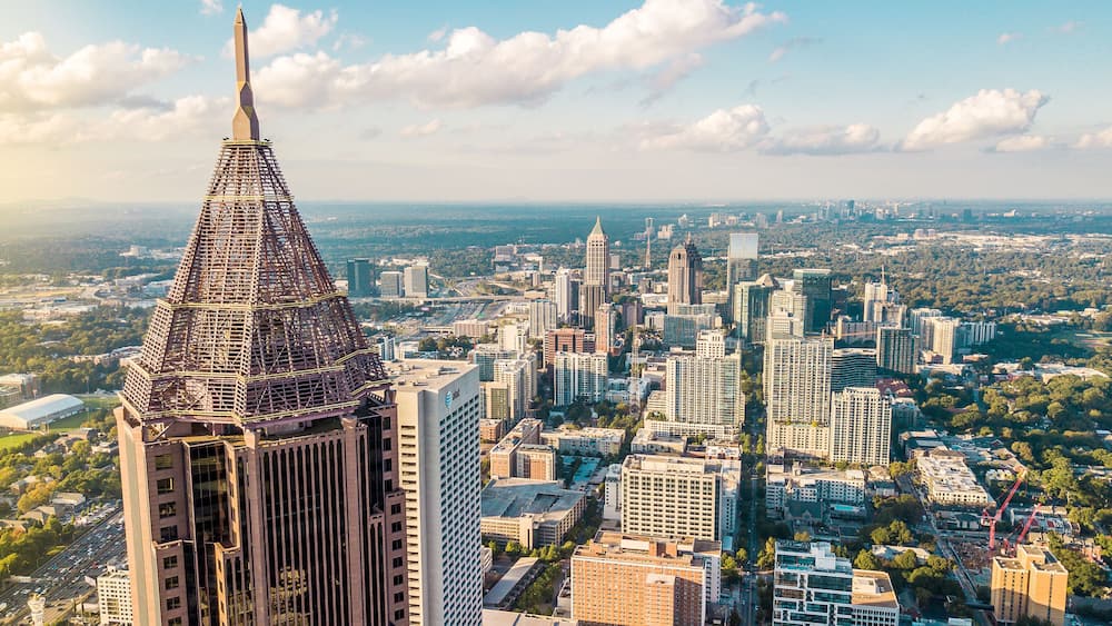 Une vue urbaine avec un gratte-ciel imposant, surmonté d’une flèche pointue, entouré de bâtiments urbains denses et dominé par un ciel dégagé.
